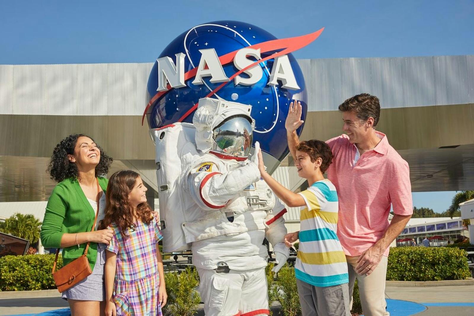 Onnellinen perhe Kennedy Space Centerin logon edessä